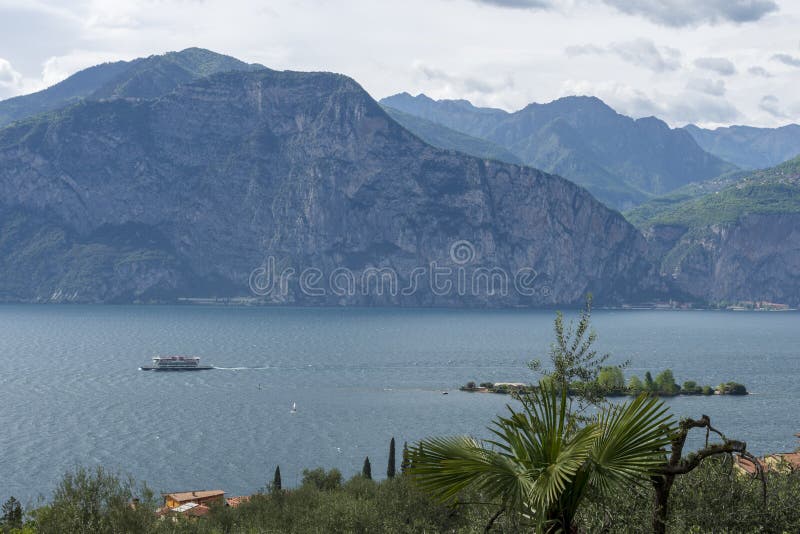 Policier de lac avec un croisement et montagnes et un ciel nuageux i de bateau image stock Policier de lac avec un croisement et montagnes et un ciel nuageux i de bateau image stock
