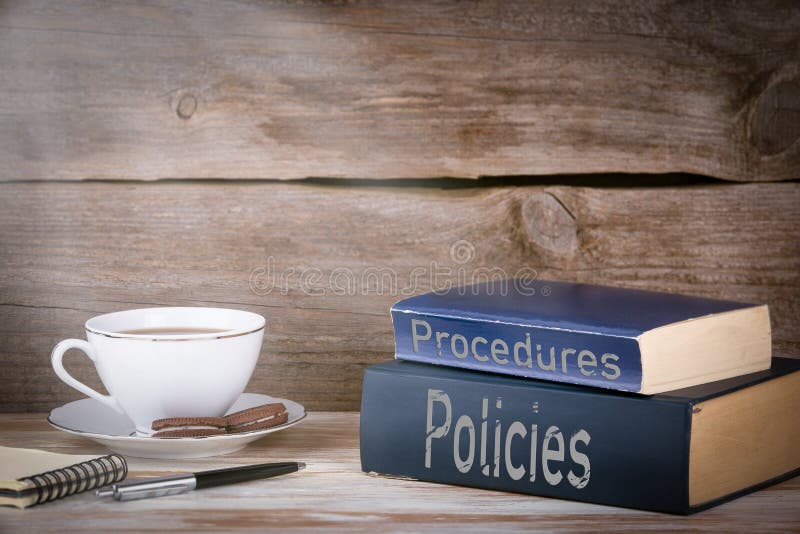 Policies and Procedures. Stack of books on wooden desk