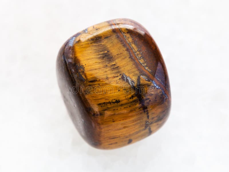 polished tiger-eye gem stone on white marble stock images polished tiger-eye gem stone on white marble stock images