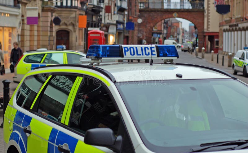 Police car side on with various police vehicles in the background at the scene of a public disturbance. Police car side on with various police vehicles in the background at the scene of a public disturbance