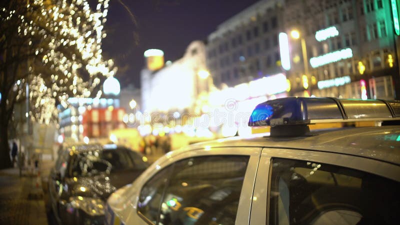 Politiewagen bij de plaats van het massaprotest, ambtenaar die overvolle stadsstraat patrouilleren bij nacht