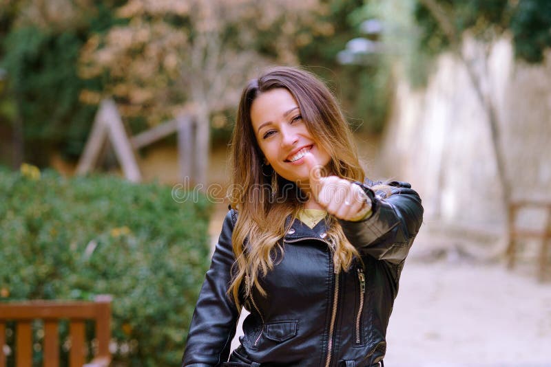 Pollice gesturing womansmiling felice su in parco fotografia stock libera da diritti