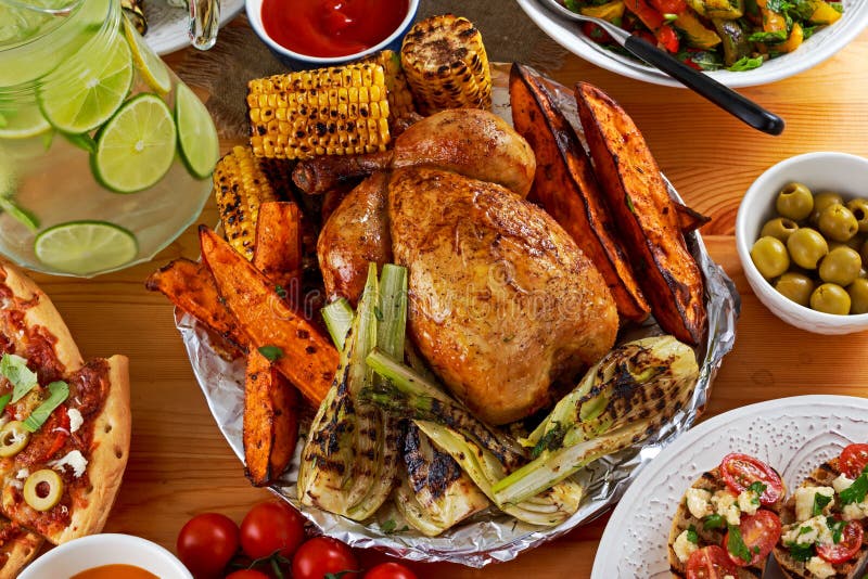 Pollo arrostito con la patata dolce al forno, il mais ed il finocchio sulla tavola del partito fotografia stock Pollo arrostito con la patata dolce al forno, il mais ed il finocchio sulla tavola del partito fotografia stock