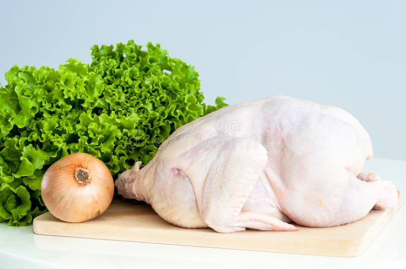 Whole raw chicken with vegetables on a cutting board. Whole raw chicken with vegetables on a cutting board