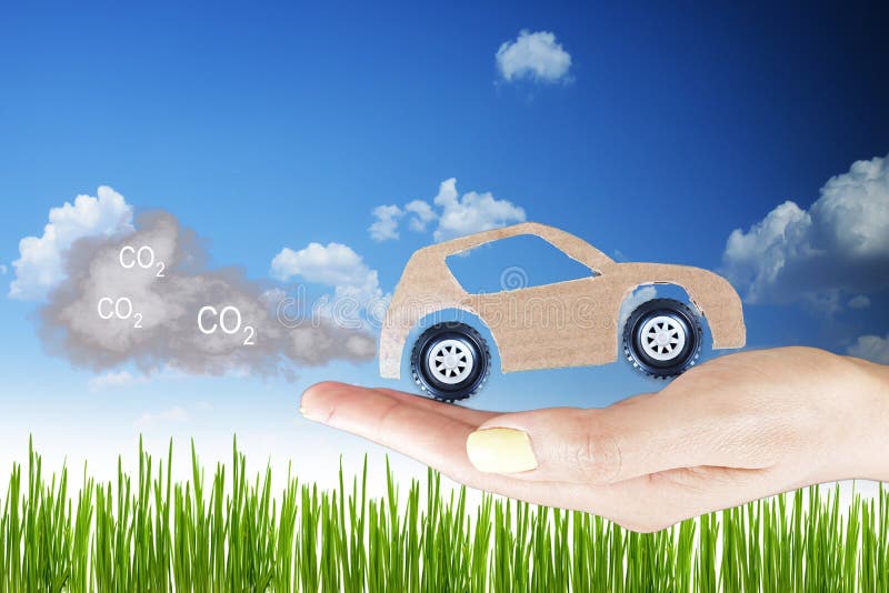 Pollution concept, cardboard car with exhaust gases in woman hand against green grass field