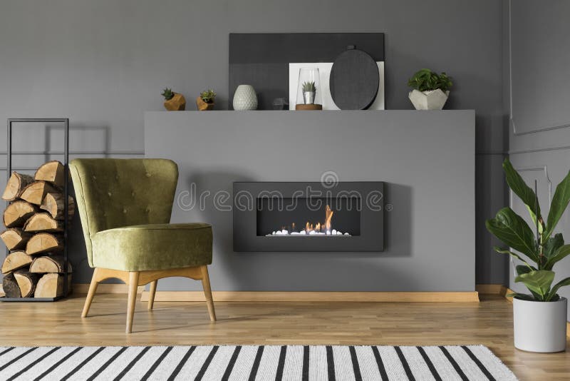 Poltrona e legna da ardere verdi accanto al camino in roo vivente grigio immagini stock libere da diritti Poltrona e legna da ardere verdi accanto al camino in roo vivente grigio immagini stock libere da diritti