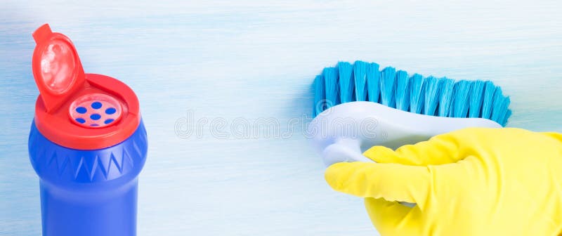 Polvere per le superfici di pulizia in una latta blu ed in una mano gomma-gloved che tengono una spazzola su un fondo leggero immagine stock libera da diritti Polvere per le superfici di pulizia in una latta blu ed in una mano gomma-gloved che tengono una spazzola su un fondo leggero immagine stock libera da diritti