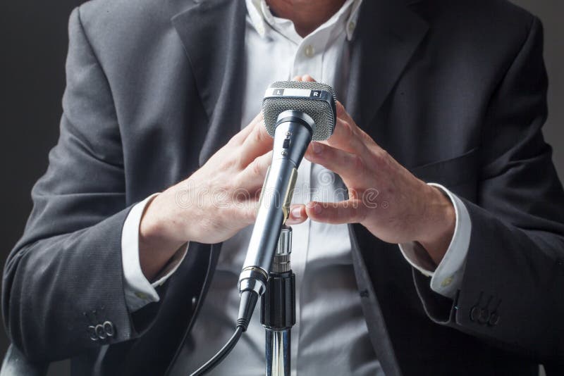 Político de sexo masculino que habla en un micrófono con el foco en sus manos foto de archivo libre de regalías Político de sexo masculino que habla en un micrófono con el foco en sus manos foto de archivo libre de regalías