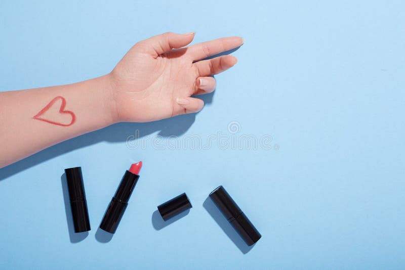Pomadki uderzenia test na kobiety ` s ręce, mieszkanie nieatutowy, stołowy odgórny widok, błękitny tło zdjęcia royalty free Pomadki uderzenia test na kobiety ` s ręce, mieszkanie nieatutowy, stołowy odgórny widok, błękitny tło zdjęcia royalty free