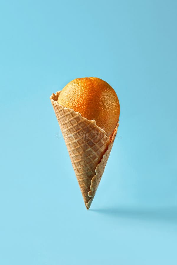 Pomarańczowy jak lody leży w stożku gofrowym na jasnoniebieskim tle. deseń