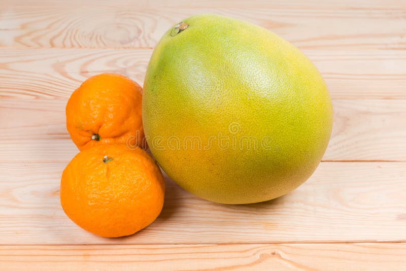Pomelo and Two Mandarin Oranges on a Wooden Rustic Table Stock Photo
