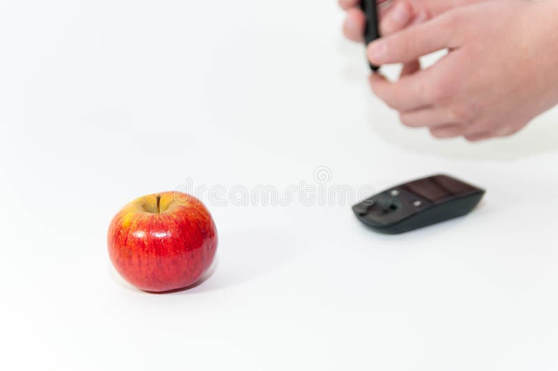 Pomme saine au foyer, mains caucasiennes à l'arrière-plan avec le glucometer photographie stock Pomme saine au foyer, mains caucasiennes à l'arrière-plan avec le glucometer photographie stock