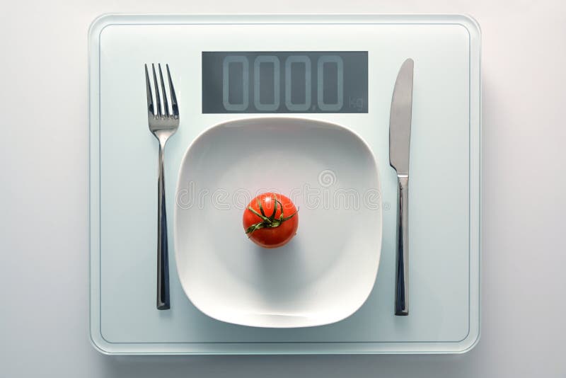 Tomato on a white plate and cutlery on a personal weight scale showing zero, healthy diet and slimming concept, copy space, high angle view from above. Tomato on a white plate and cutlery on a personal weight scale showing zero, healthy diet and slimming concept, copy space, high angle view from above