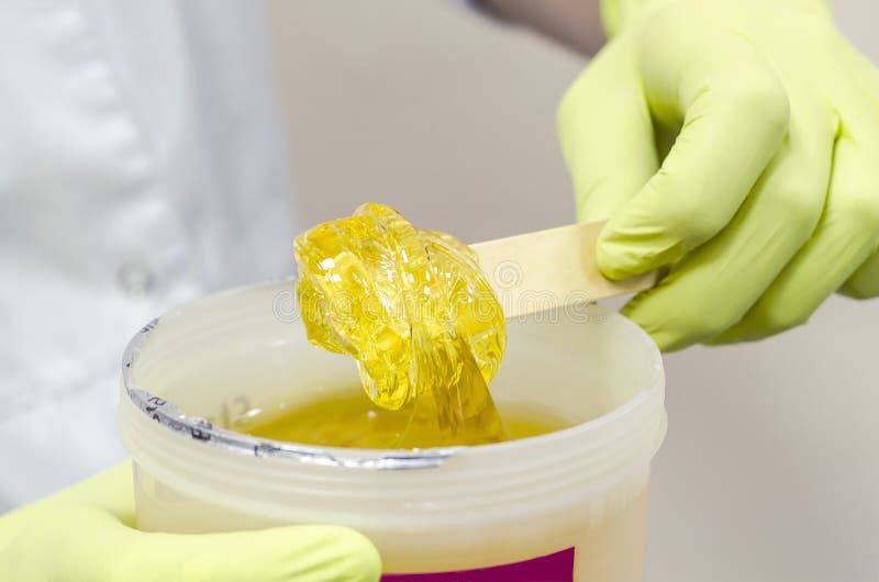 Pompa di pasta di zucchero o di cera di miele su una spatola di legno in mano di un estetista concetto di bellezza fotografia stock libera da diritti Pompa di pasta di zucchero o di cera di miele su una spatola di legno in mano di un estetista concetto di bellezza fotografia stock libera da diritti