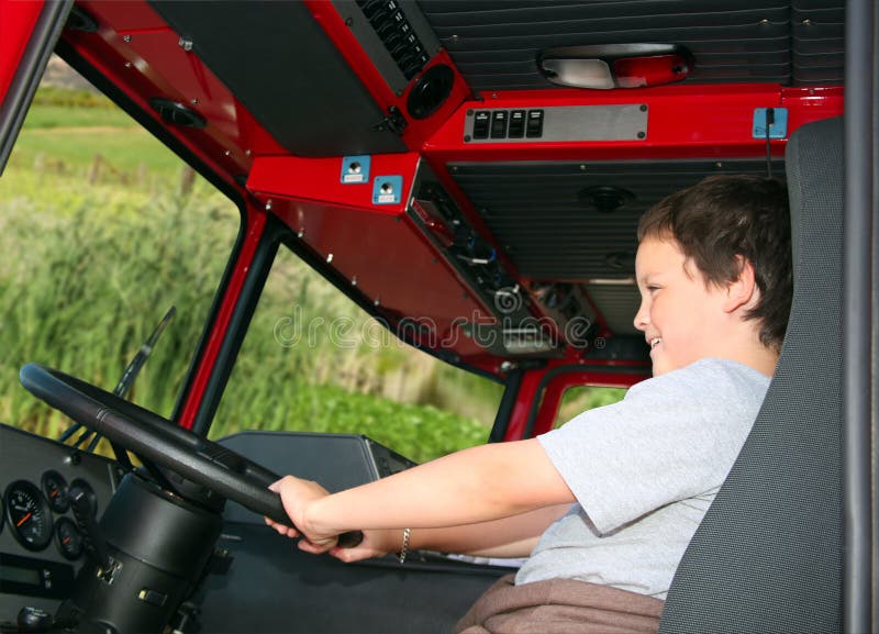 Young boy pretending to drive a fire truck. Young boy pretending to drive a fire truck