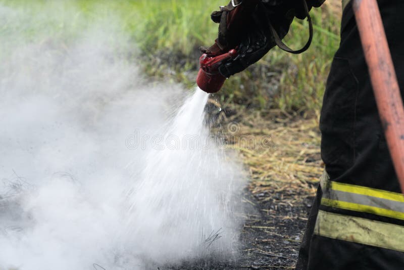 Pompiere durante l'estinguente, preparandosi per sormontare zona di fuoco di addestramento psicologico per i pompieri immagini stock Pompiere durante l'estinguente, preparandosi per sormontare zona di fuoco di addestramento psicologico per i pompieri immagini stock