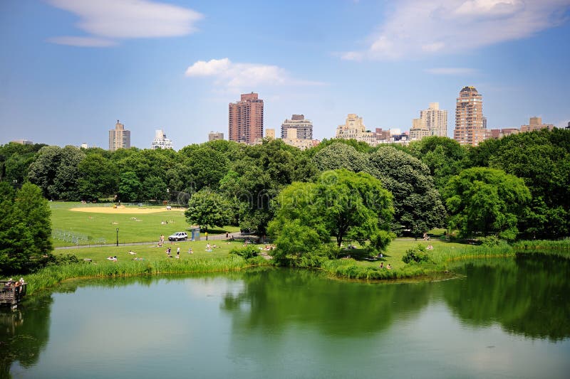 Rybník v New York City Central Parku v létě s výhledem na Manhattanské mrakodrapy a barevné stromy.