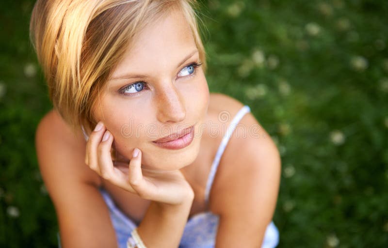 Pondering a summers day away. a beautiful young woman sitting outiside.