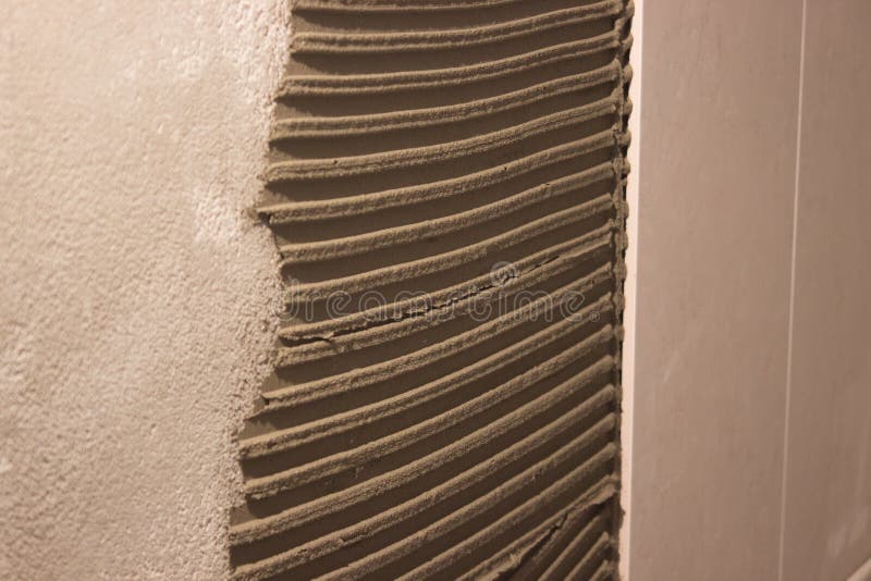 Ponendo le piastrelle di ceramica sul mortaio del cemento la distribuzione della soluzione ha calcolato la spatola sulla parete p fotografie stock libere da diritti Ponendo le piastrelle di ceramica sul mortaio del cemento la distribuzione della soluzione ha calcolato la spatola sulla parete p fotografie stock libere da diritti