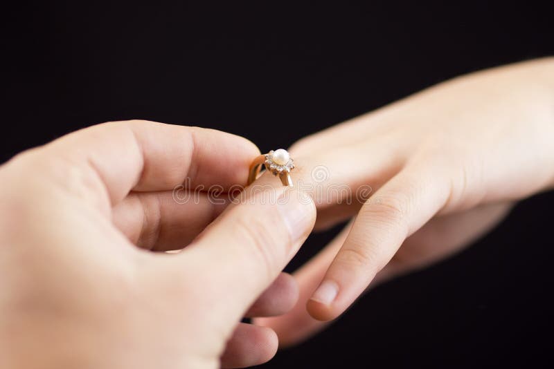 Poner un anillo en la mano de la muchacha imagenes de archivo Poner un anillo en la mano de la muchacha imagenes de archivo
