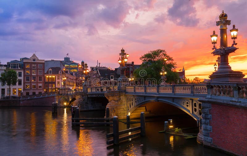 Pont bleu de Blauwbrug au-dessus de rivière d'Amstel à Amsterdam à la soirée de ressort de coucher du soleil, Hollande photographie stock libre de droits Pont bleu de Blauwbrug au-dessus de rivière d'Amstel à Amsterdam à la soirée de ressort de coucher du soleil, Hollande photographie stock libre de droits