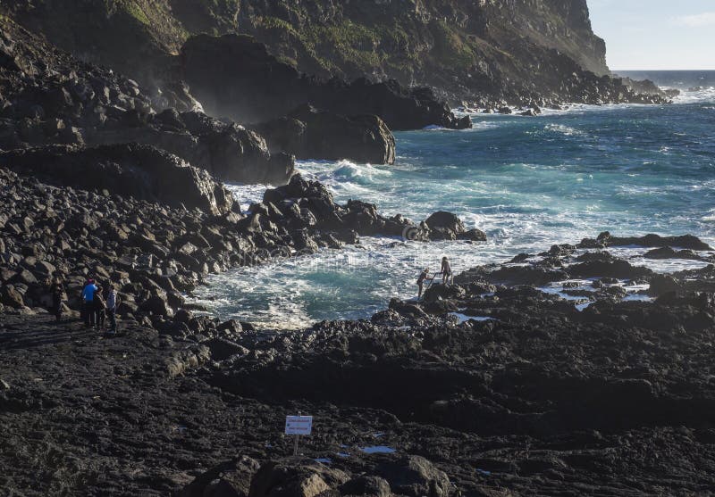 Ponta DA Ferraria, sao Miguel Island, îles des Açores, Portugal le 26 décembre 2018 : jeune womaman essayant au climbe vers le ba photos stock Ponta DA Ferraria, sao Miguel Island, îles des Açores, Portugal le 26 décembre 2018 : jeune womaman essayant au climbe vers le ba photos stock