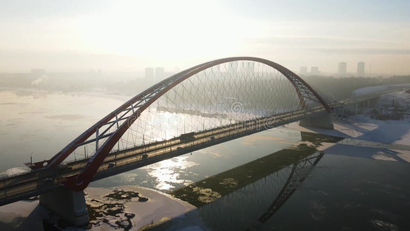 Ponte cinzenta contra o pano de fundo do sol e da névoa. ponte de novosibirsk no inverno. antena 4k