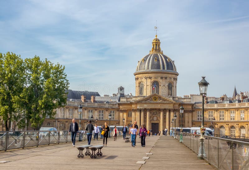 France. Summer day in Paris. People on the Footbridge of the Arts and Mazarine Library in the background. France. Summer day in Paris. People on the Footbridge of the Arts and Mazarine Library in the background