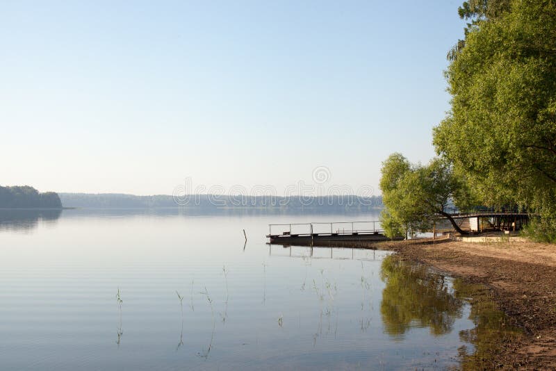Ponte di pesca sulla riva di un lago della foresta nel primo mattino nella nebbia fotografie stock libere da diritti Ponte di pesca sulla riva di un lago della foresta nel primo mattino nella nebbia fotografie stock libere da diritti