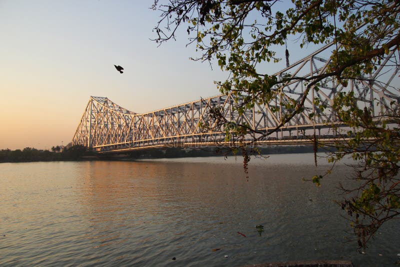 A view of the Howrah bridge from the banks of the river Hooghly.  Howrah  Bridge is a bridge with a suspended span over the Hooghly River in West Bengal, India. Commissioned in 1943, the bridge was originally named the New Howrah Bridge, because it replaced a pontoon bridge at the same location linking the two cities of Howrah and Kolkata. A view of the Howrah bridge from the banks of the river Hooghly.  Howrah  Bridge is a bridge with a suspended span over the Hooghly River in West Bengal, India. Commissioned in 1943, the bridge was originally named the New Howrah Bridge, because it replaced a pontoon bridge at the same location linking the two cities of Howrah and Kolkata.