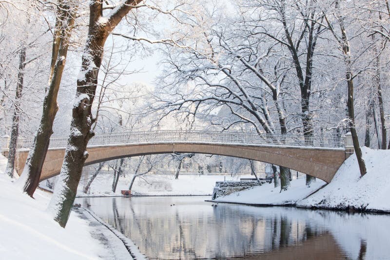 Ponte pedonale nell'inverno sopra il canale di Riga vicino a Bastejkalns fotografie stock Ponte pedonale nell'inverno sopra il canale di Riga vicino a Bastejkalns fotografie stock