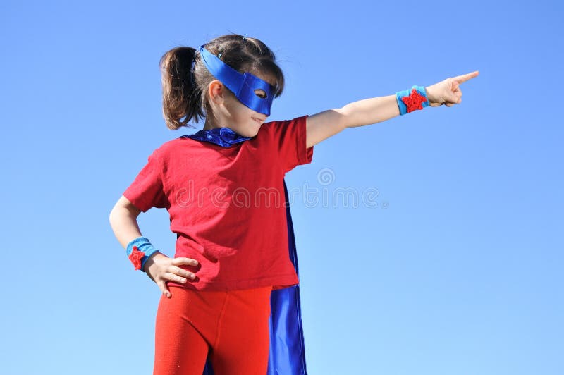 Pontos da menina do super-herói para o céu azul dramático fotografia de stock