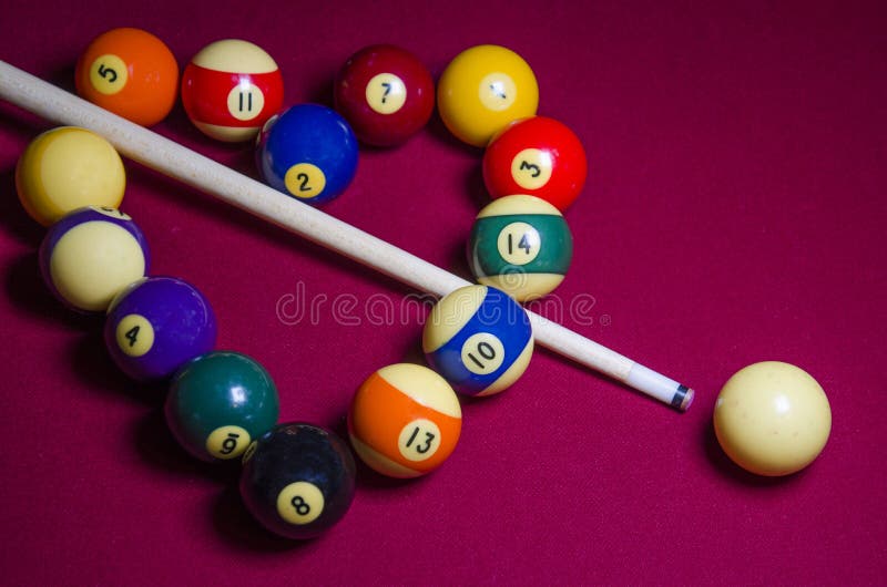 An artistic dramatic shot of a Red Felt Pool Table with Pool sticks and the vintage old balls. Focus is on the front balls in image. Shallow depth of field on purpose. An artistic dramatic shot of a Red Felt Pool Table with Pool sticks and the vintage old balls. Focus is on the front balls in image. Shallow depth of field on purpose.