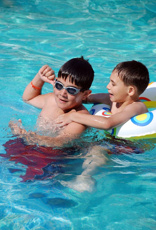 Cute Young Boys Jumping into a Swimming Pool while on a Fun Vacation