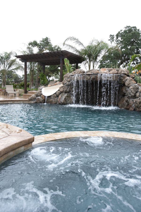 A pool with a waterfall in a luxury backyard
