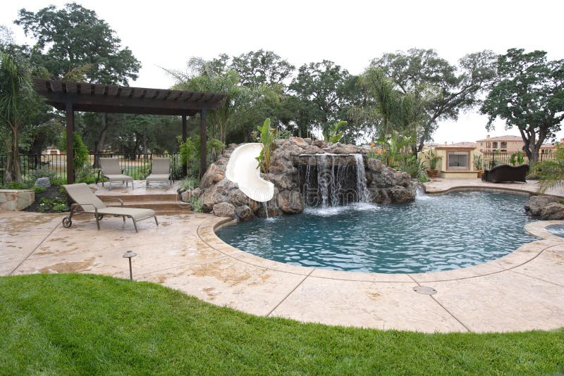 A pool with a waterfall in a luxury backyard stock images