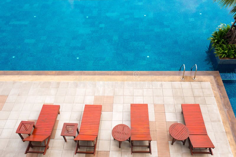Poolside deckchairs alongside blue swimming pool royalty free stock photography