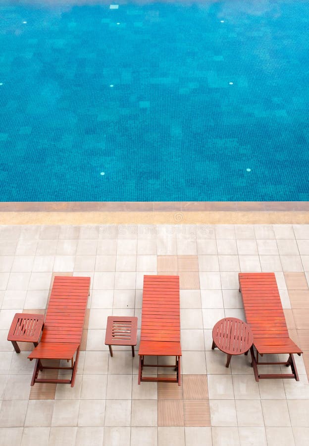 Poolside deckchairs alongside blue swimming pool