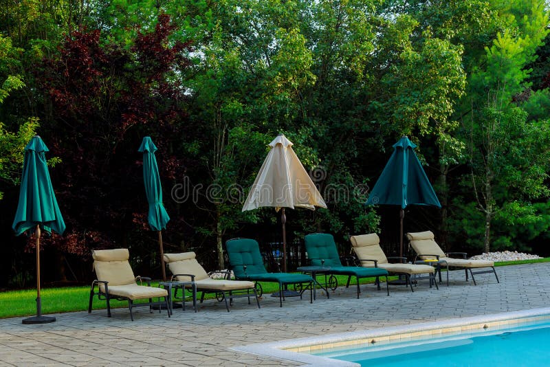Poolside deckchairs with blue swimming pool stock image