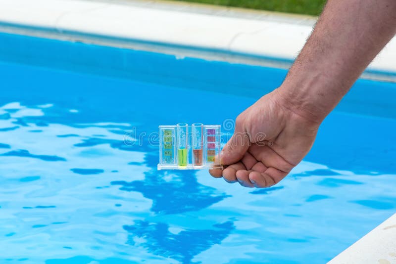 Tester for pool in a hand against the background of the swimming pool. Tester for pool in a hand against the background of the swimming pool.