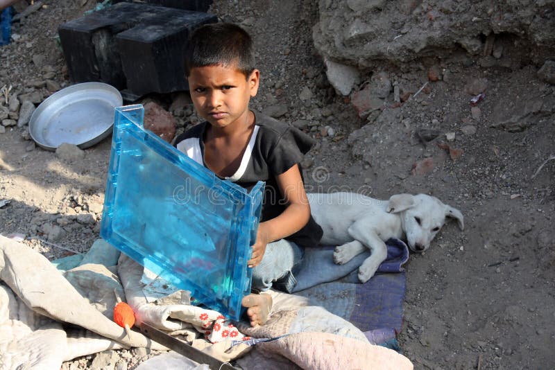 Chudé chlapce, jak sedí na ulici s jeho bílého psa v Indii.