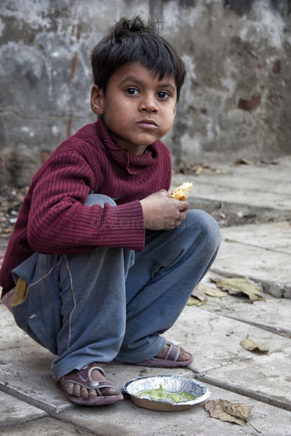 A poor boy looking eating by the road side in new delhi