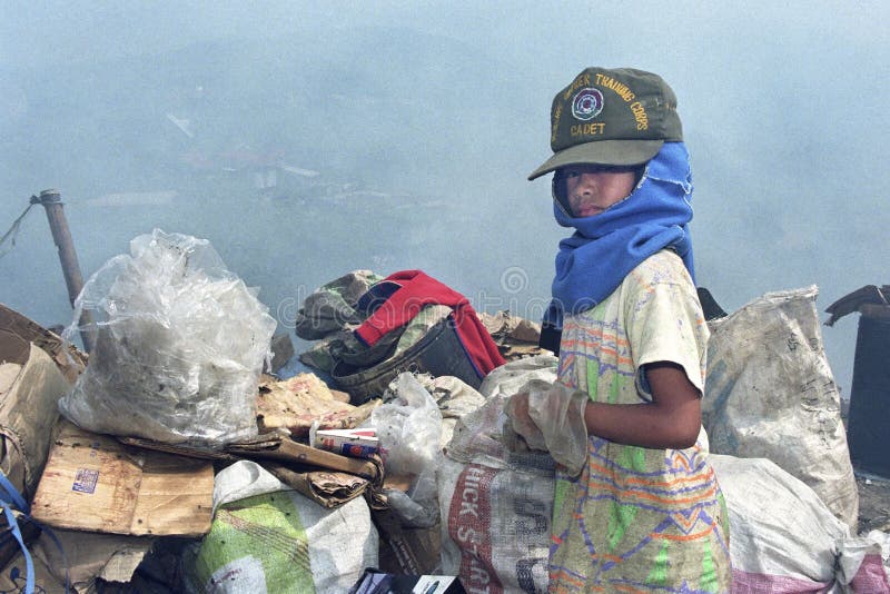 Poor Filipino boy gathering plastic, paper on landfill