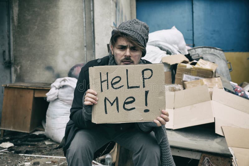 Poor young man with HELP ME sign at dump.