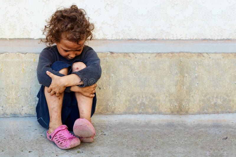 Poor, sad little child against the concrete wall stock images
