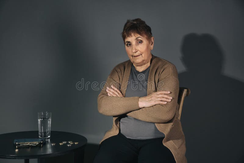 Poor senior woman with water and coins at table on grey background royalty free stock images