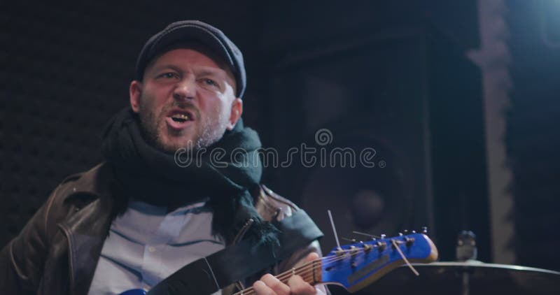 Popgroepvocalist het zingen en het spelen gitaar bij repetitie