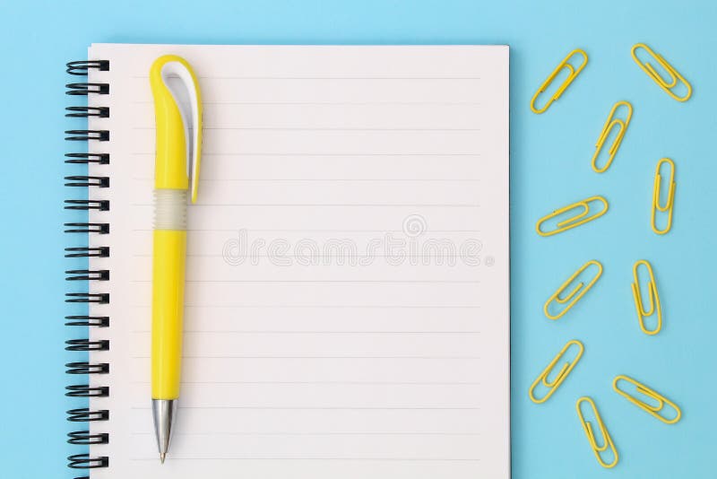 Popiera szko?y kreatywnie poj?cie Notepad z żółtym piórem i klamerki na błękitnym tle Odg?rny widok p?aski k?a?? fotografia stock Popiera szko?y kreatywnie poj?cie Notepad z żółtym piórem i klamerki na błękitnym tle Odg?rny widok p?aski k?a?? fotografia stock