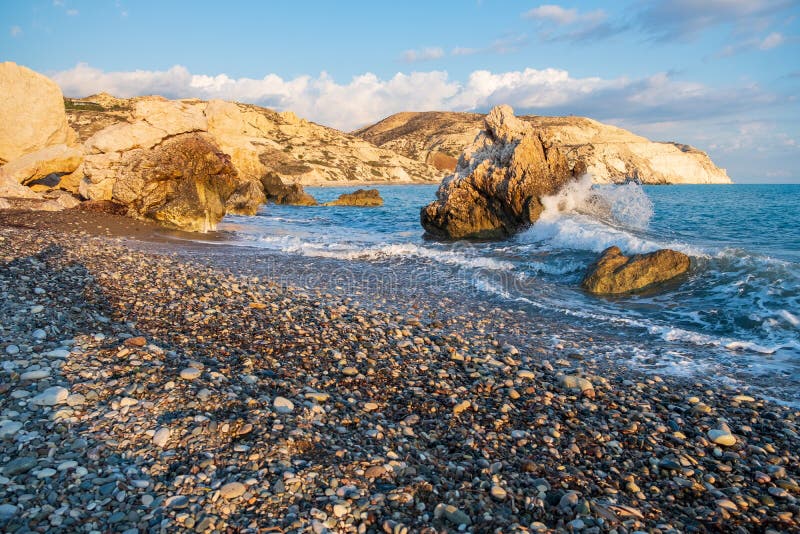 Popołudniowy widok łamanie fale przy żwirowatą plażą wokoło Petra tou Romiou, także znać jako Aphrodite miejsce narodzin w Paphos zdjęcia stock Popołudniowy widok łamanie fale przy żwirowatą plażą wokoło Petra tou Romiou, także znać jako Aphrodite miejsce narodzin w Paphos zdjęcia stock