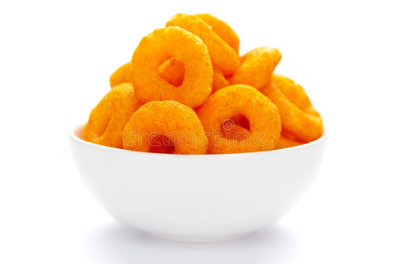 Popular Ready to eat crunchy and puffed snacks ring tangy orange color in a white ceramic bowl. Top view